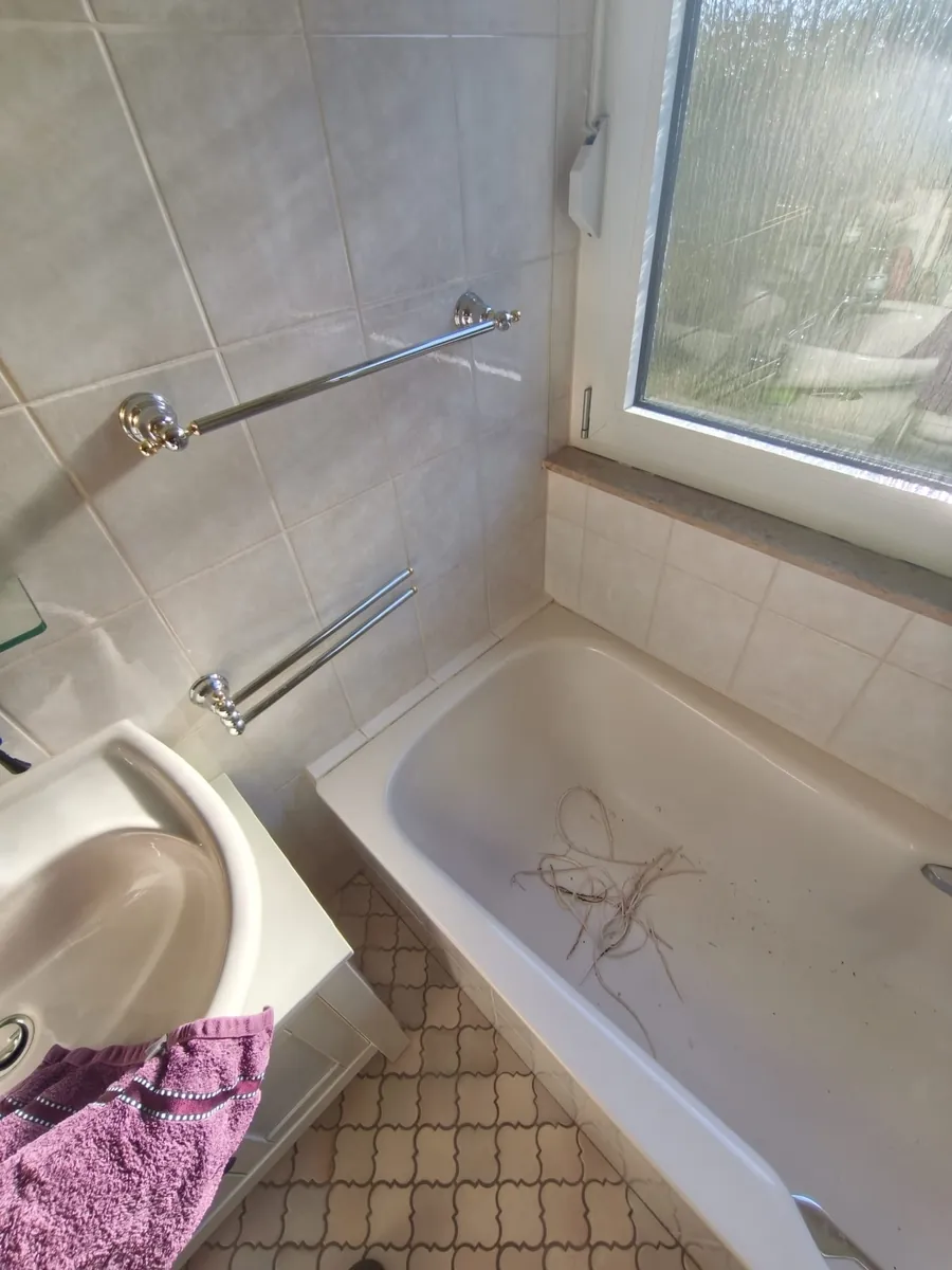 Echtes Foto: herausgeschnittene alte Silikonfugen liegen in der Wanne